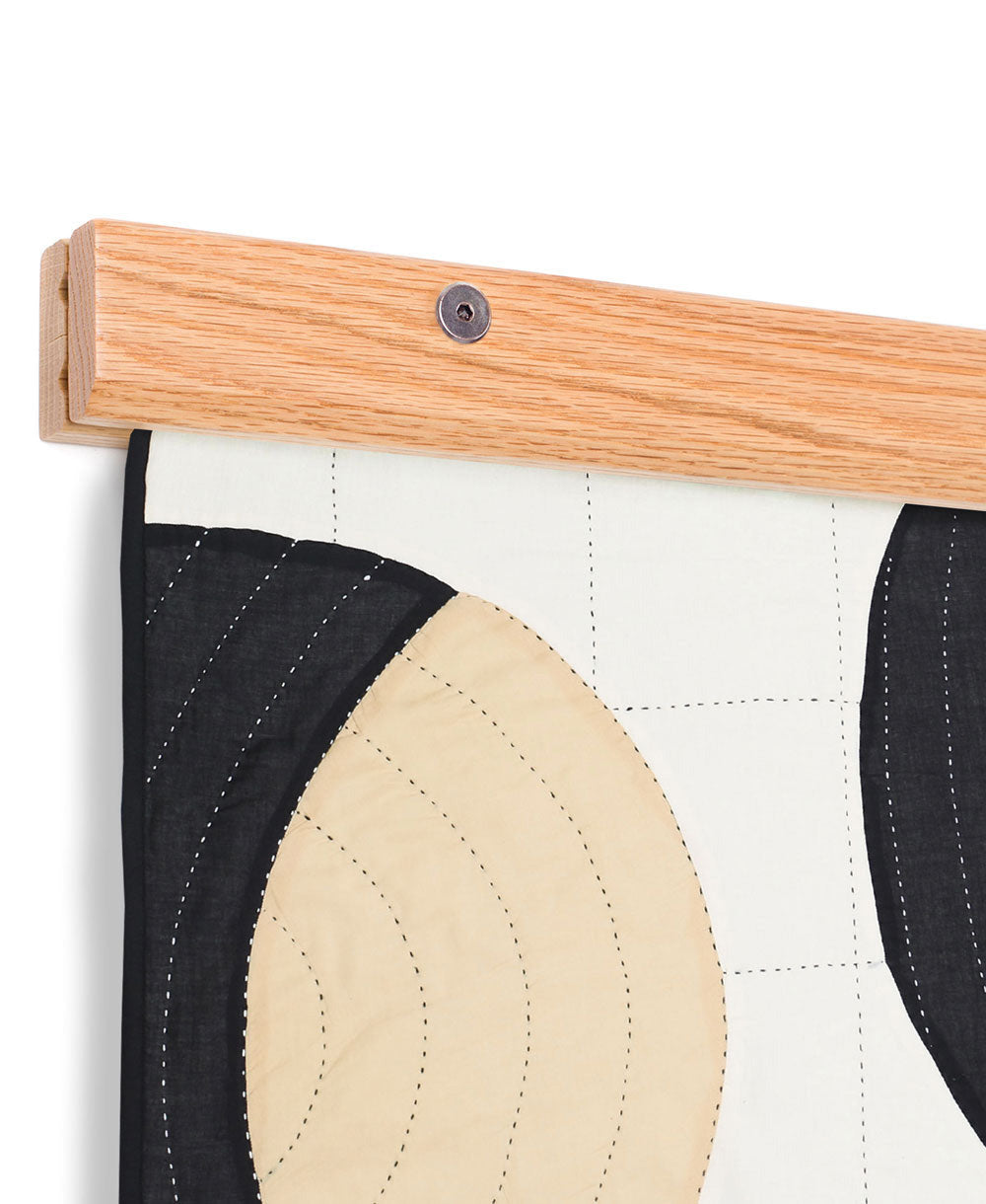 Close-up of a wooden frame with a fabric panel featuring black, beige, and white design.