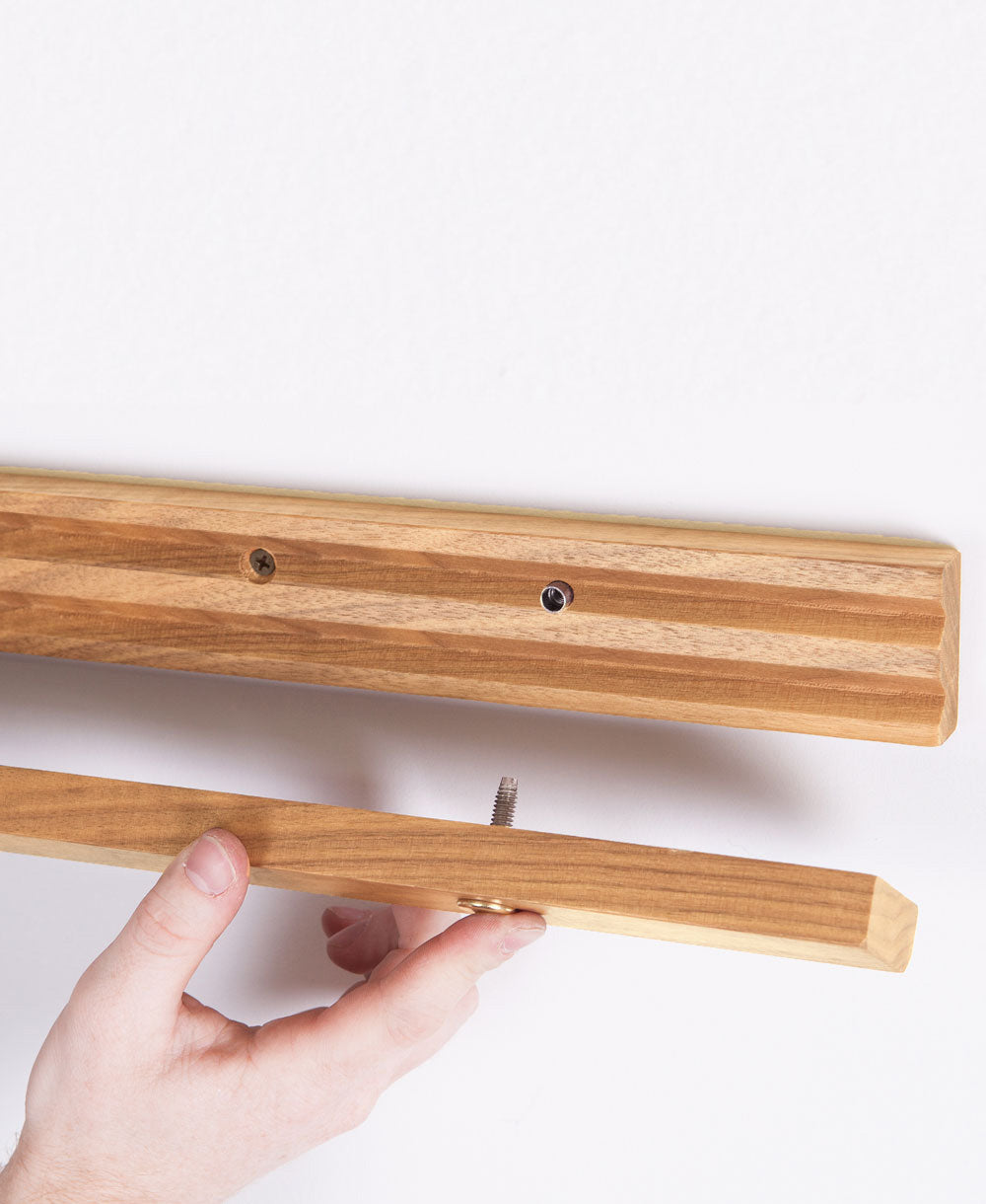 Wooden wall hooks with a hand holding one of them on a white background