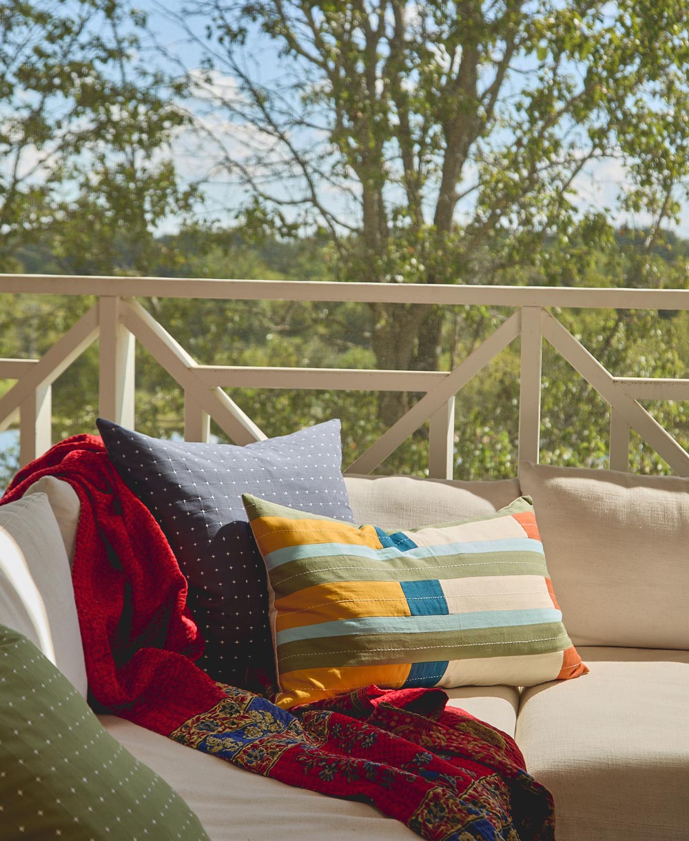 colorful striped lumbar pillow on beige sofa outdoors in sunroom