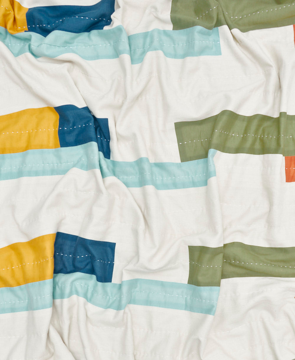 Colorful striped quilt with blue, green, yellow, and red stripes on a white background