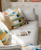 Gray sofa with colorful pillows and a magazine on a wooden floor