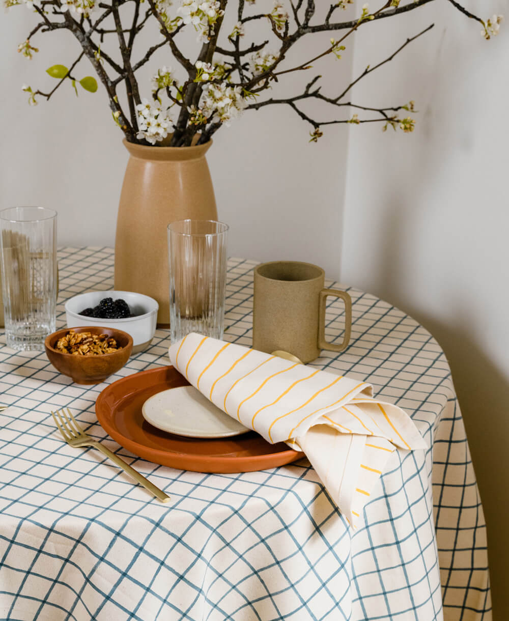 Dining table setting with a vase, plates, and glasses on a checkered tablecloth