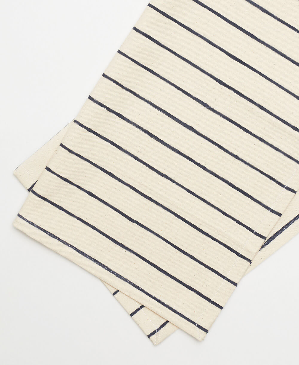 two folded striped cotton napkins with navy blue lines on a white background