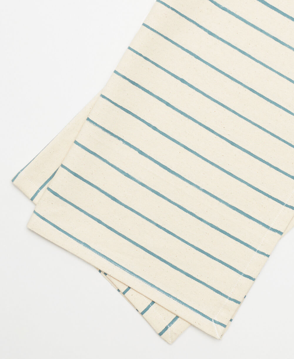 two folded striped cotton napkins in spruce green and off-white on a white background