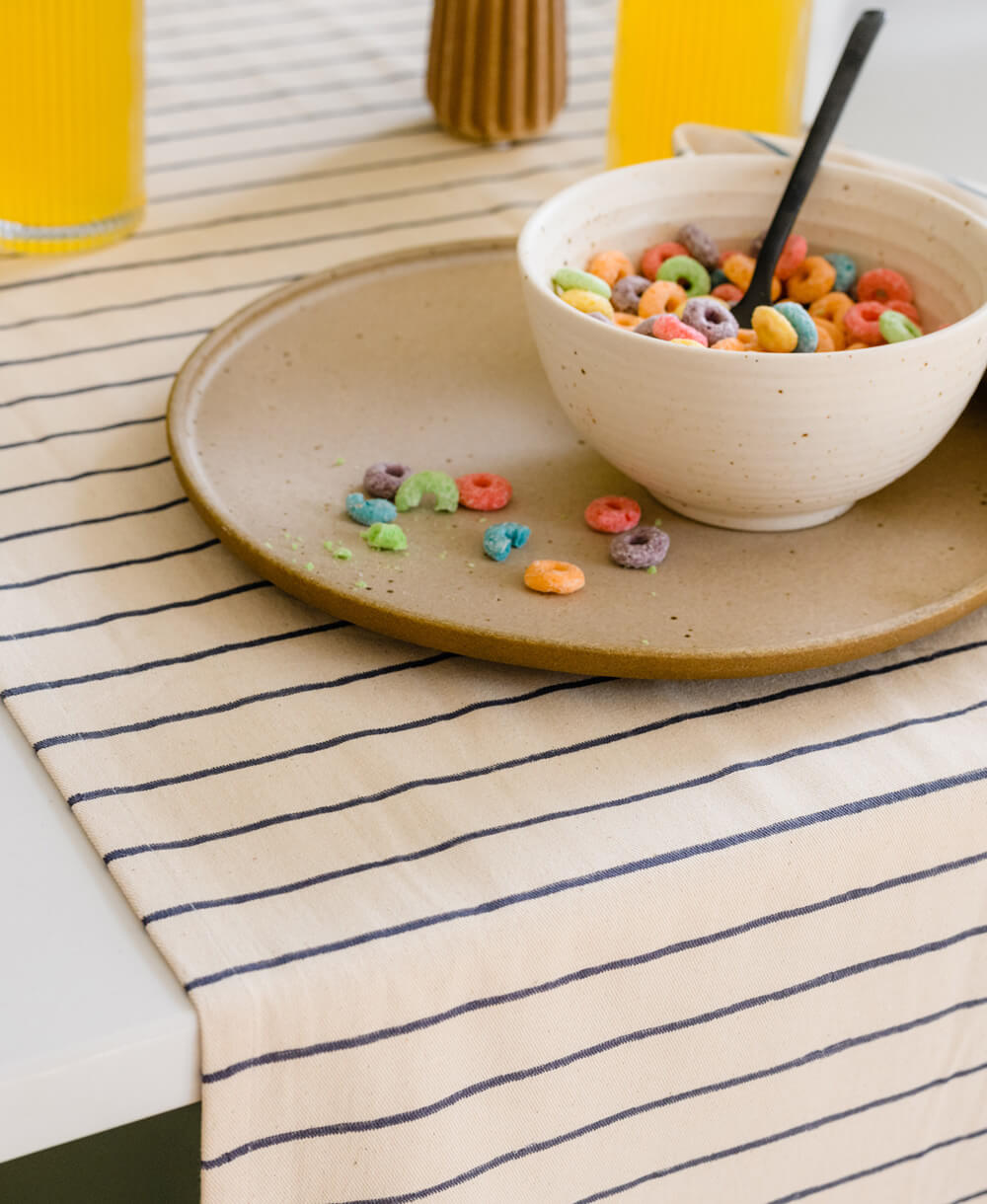 Bowl of cereal with colorful cereal pieces on a striped tablecloth