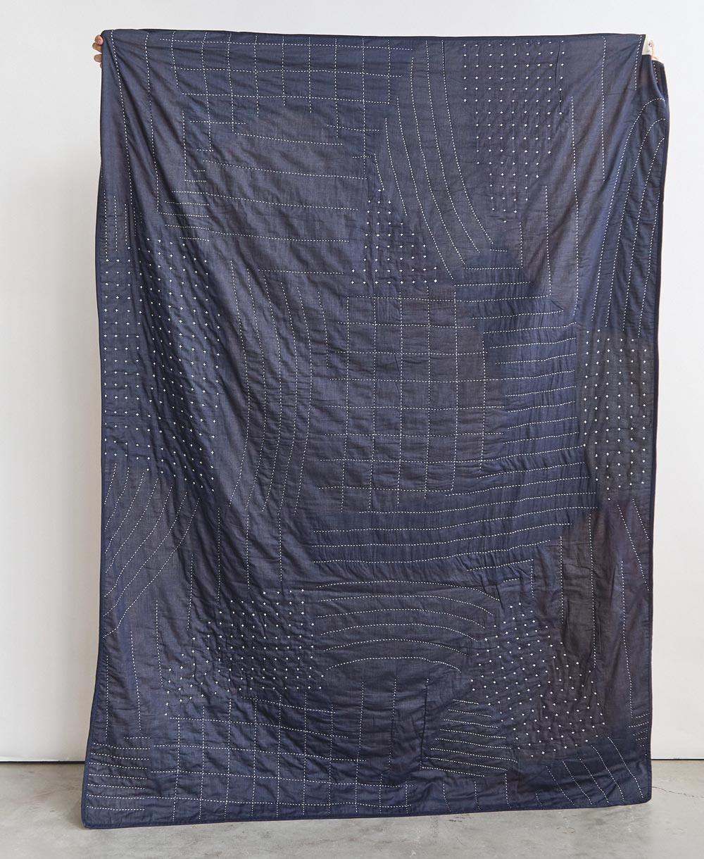 Navy quilt with geometric pattern on a white background