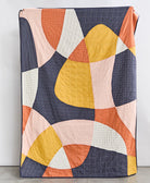 modern patchwork quilt in bold abstract shapes in yellow, navy, orange, pink and ivory