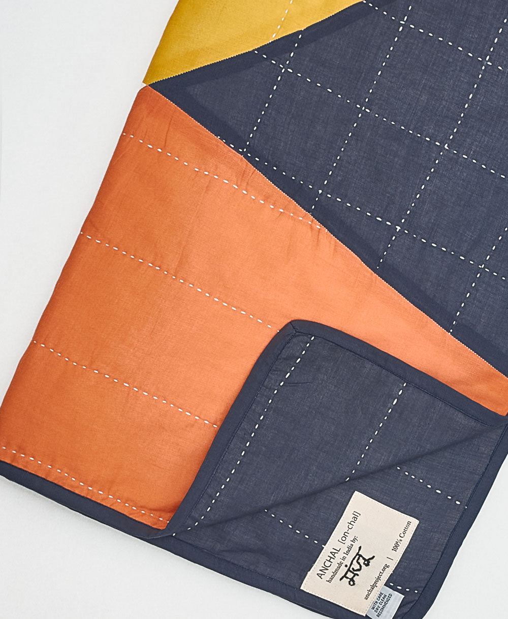 Colorful quilt with an Anchal brand label on a white background