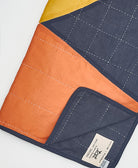 Colorful quilt with an Anchal brand label on a white background