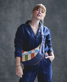 woman wearing crescent sling bag across shoulder in navy blue and multi-colored checkered print