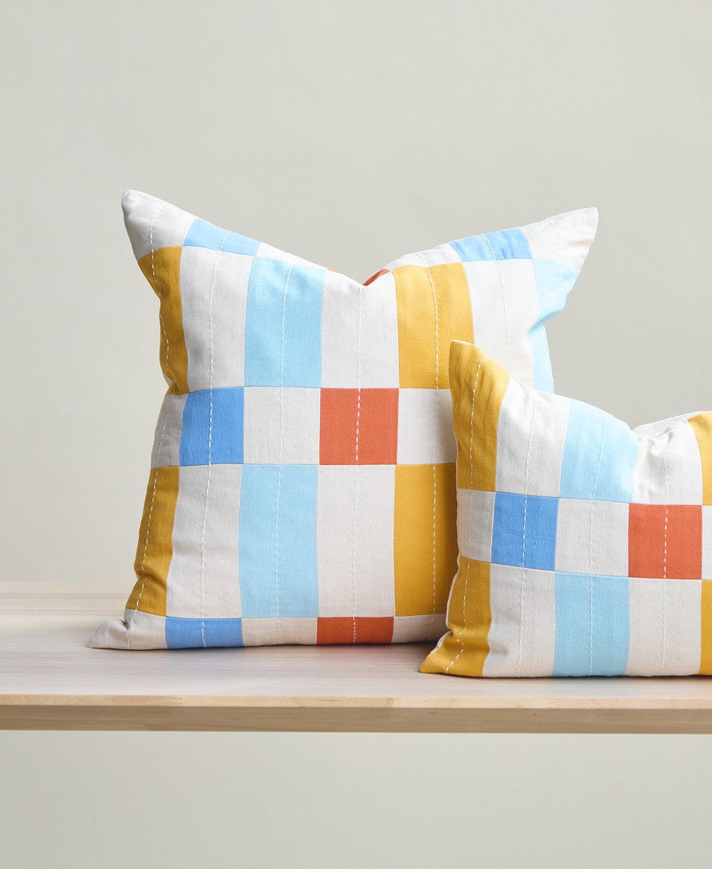 Two checkered pillows with a colorful pattern on a wooden surface.