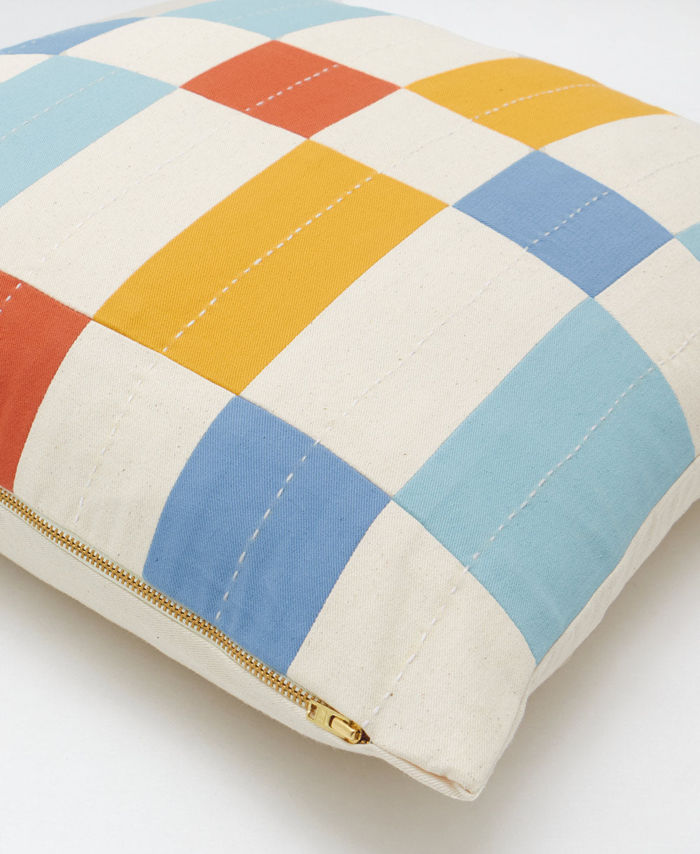 Colorful checkered pillow with a gold zipper on a white background