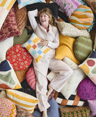 Woman lying on a pile of colorful modern throw pillows