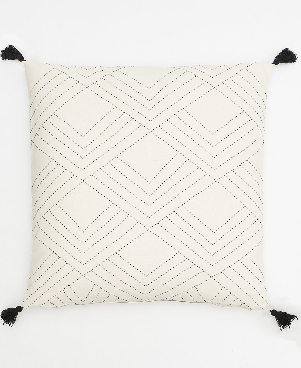 embroidered throw pillow in natural white with black stitching and black tassels