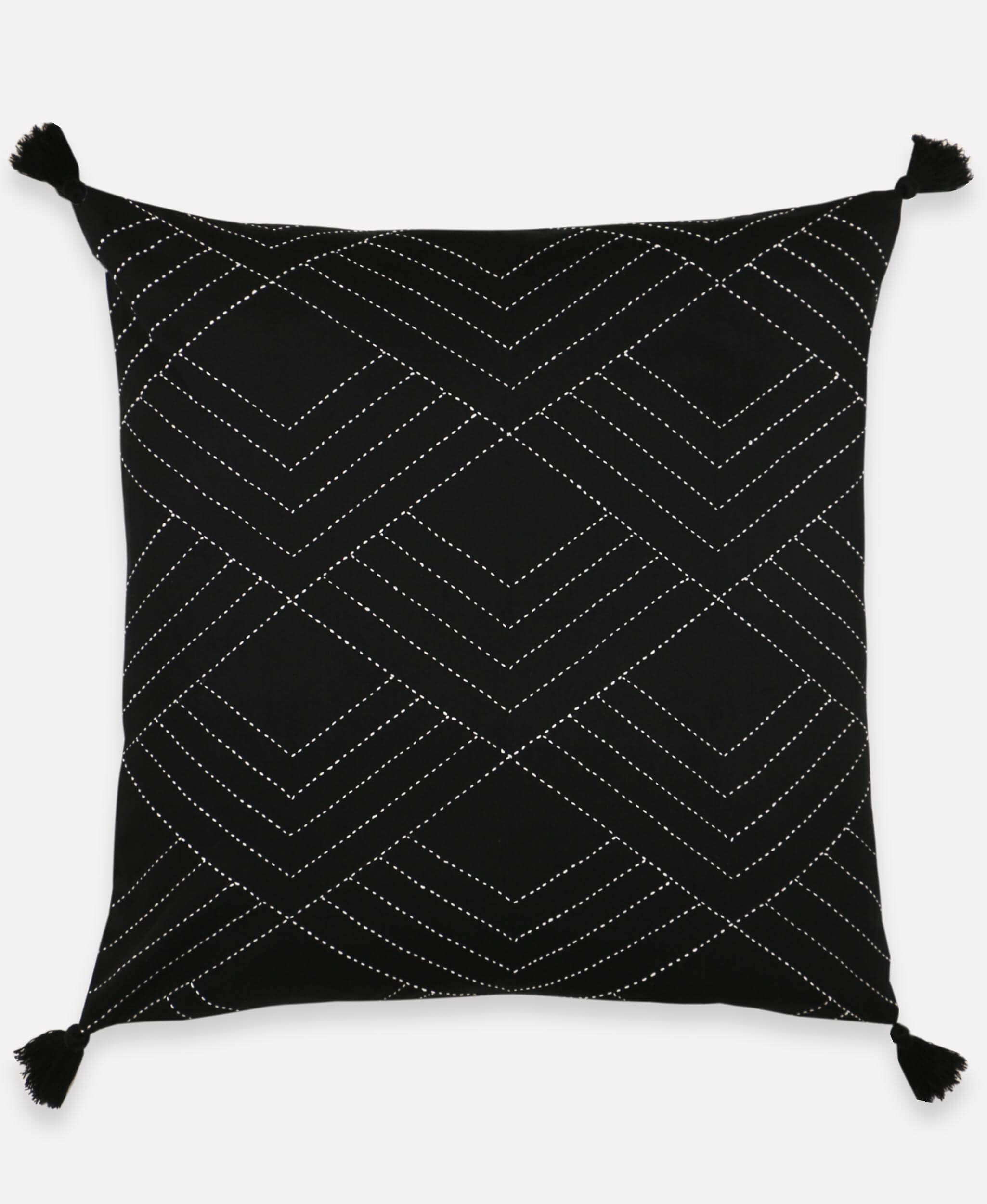 black throw pillow with white hand-stitched embroidery and black tassels