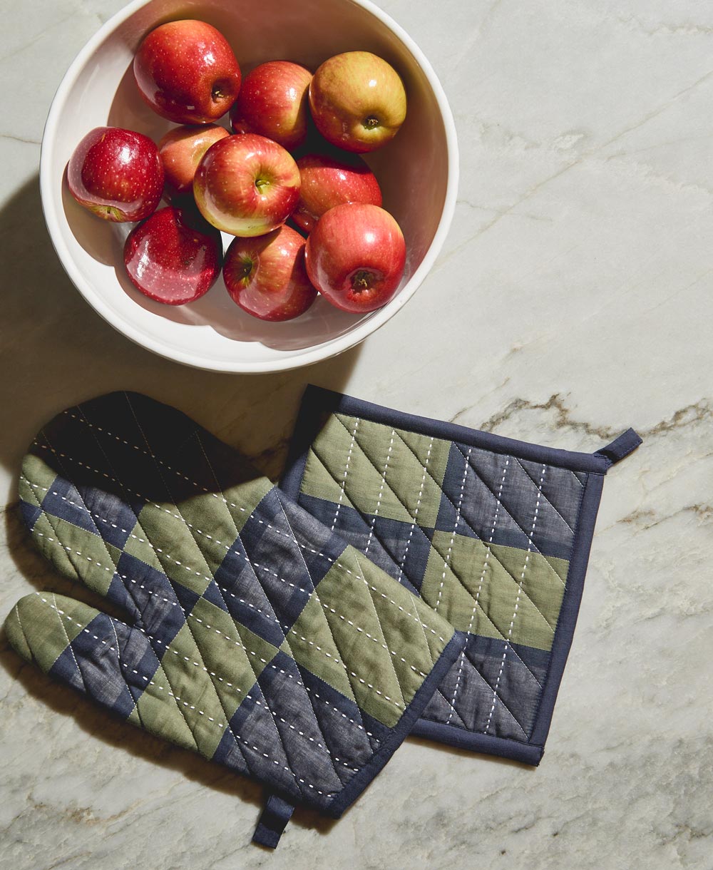 padded oven mitt and matching pot holder in hunter green and navy blue checkered pattern next to bowl of red apples