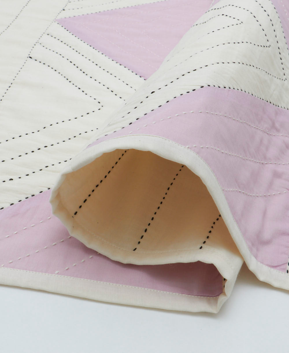 triangle baby quilt with white and lilac patchwork and black kantha stitching
