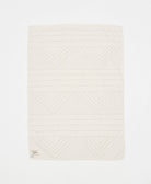 White textured blanket with geometric pattern on a white background