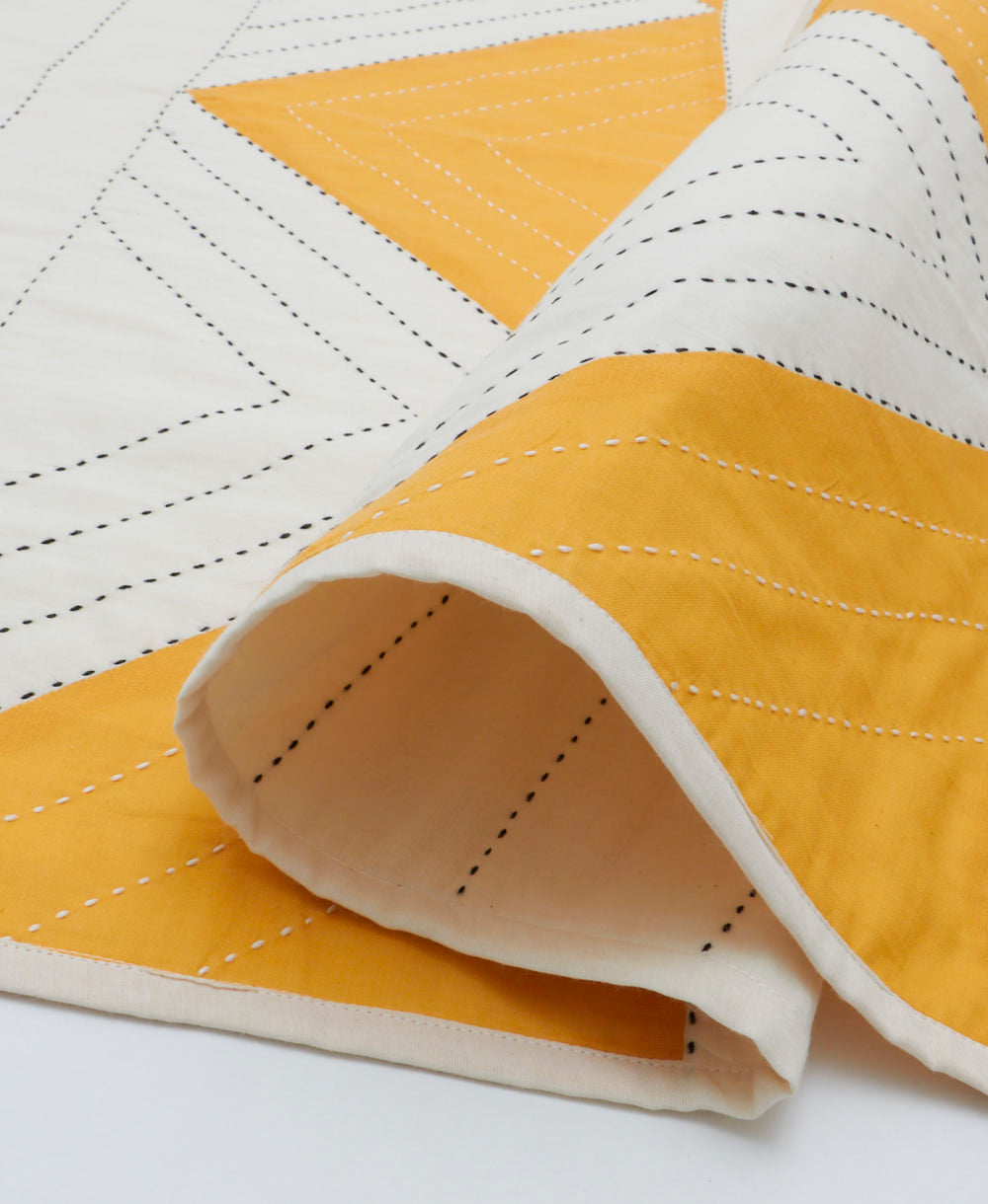 mustard yellow and white baby quilt with black kantha stitching in a geometric pattern