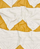 Close-up of a quilt with white and mustard yellow diamond pattern