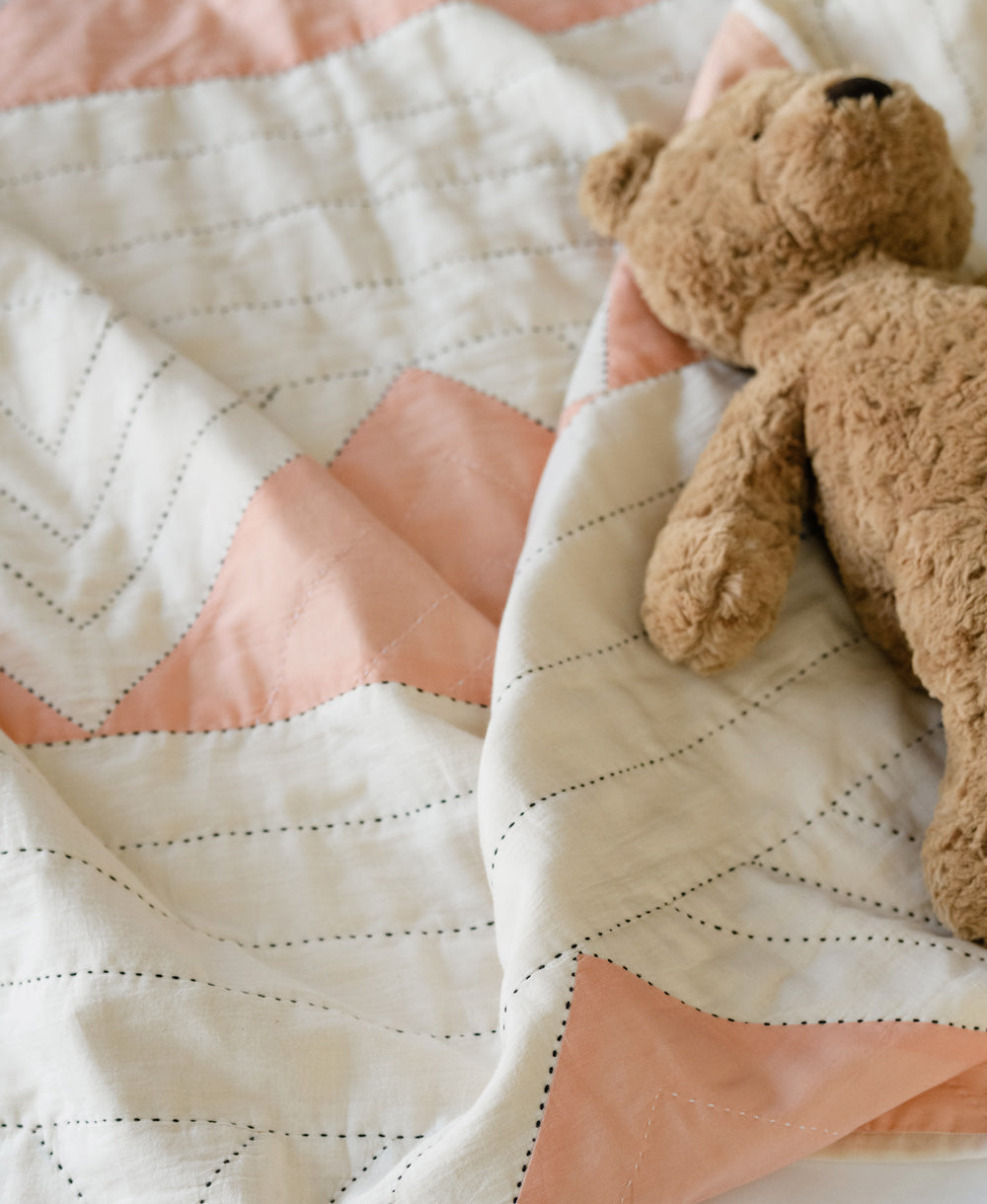 brown teddy bear on a pink and white triangle geometric baby quilt