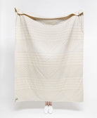 White quilt with geometric pattern draped over a person on a white background