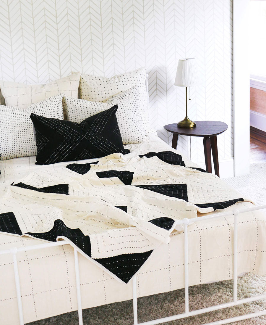 Bed with black and white patterned bedding in a bedroom setting