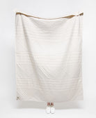 White quilt with a geometric pattern draped over a white background