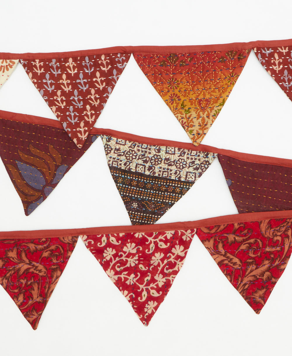 Decorative fabric triangle banner with brown and red patterns on a white background