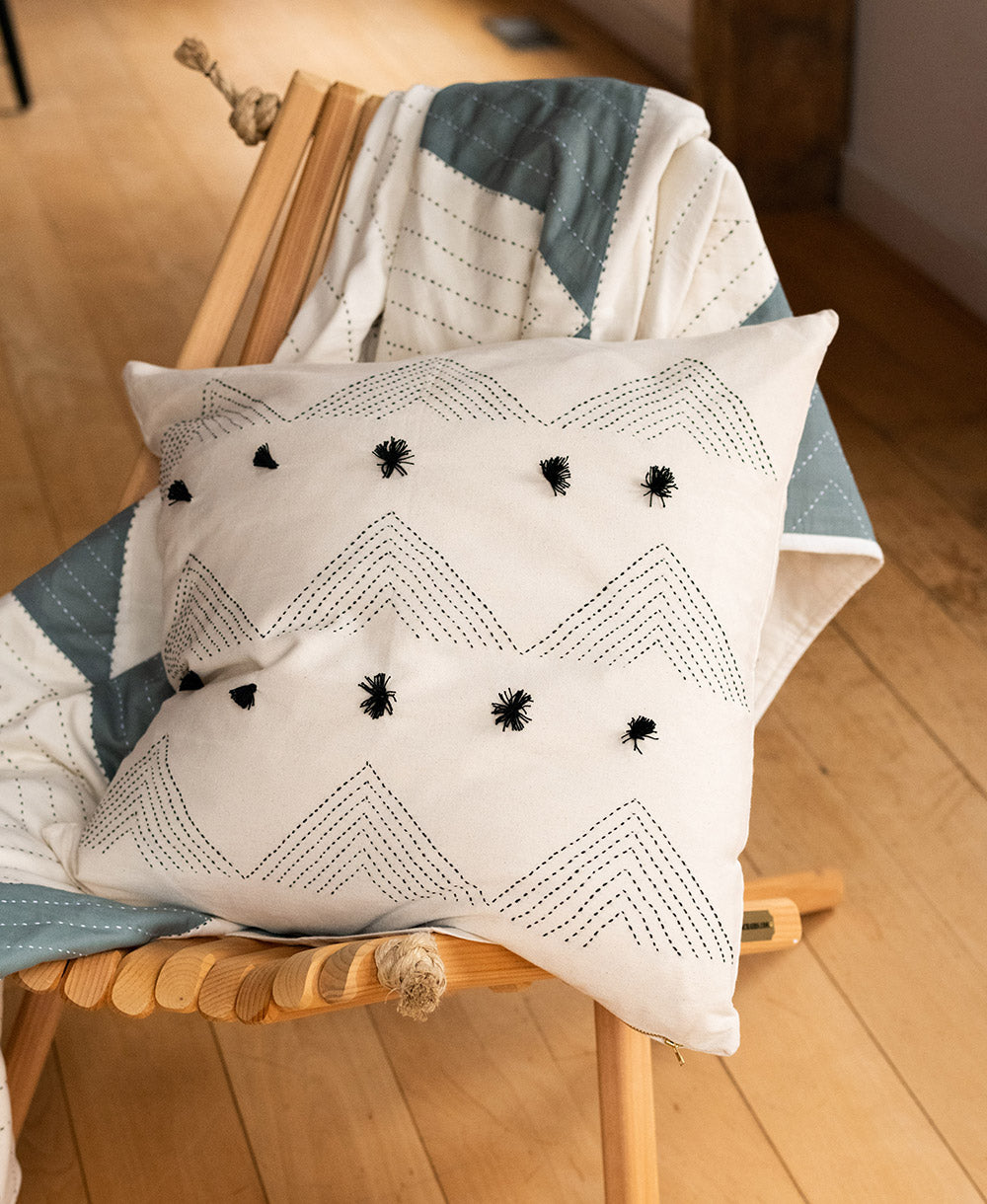 Decorative pillow with zigzag pattern and black accents on a wooden chair