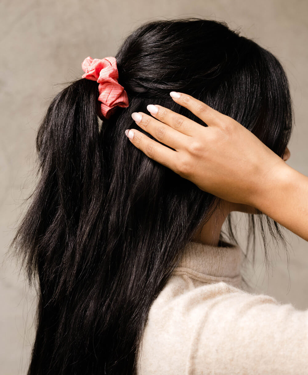pink silk scrunchie in a half-up hairstyle