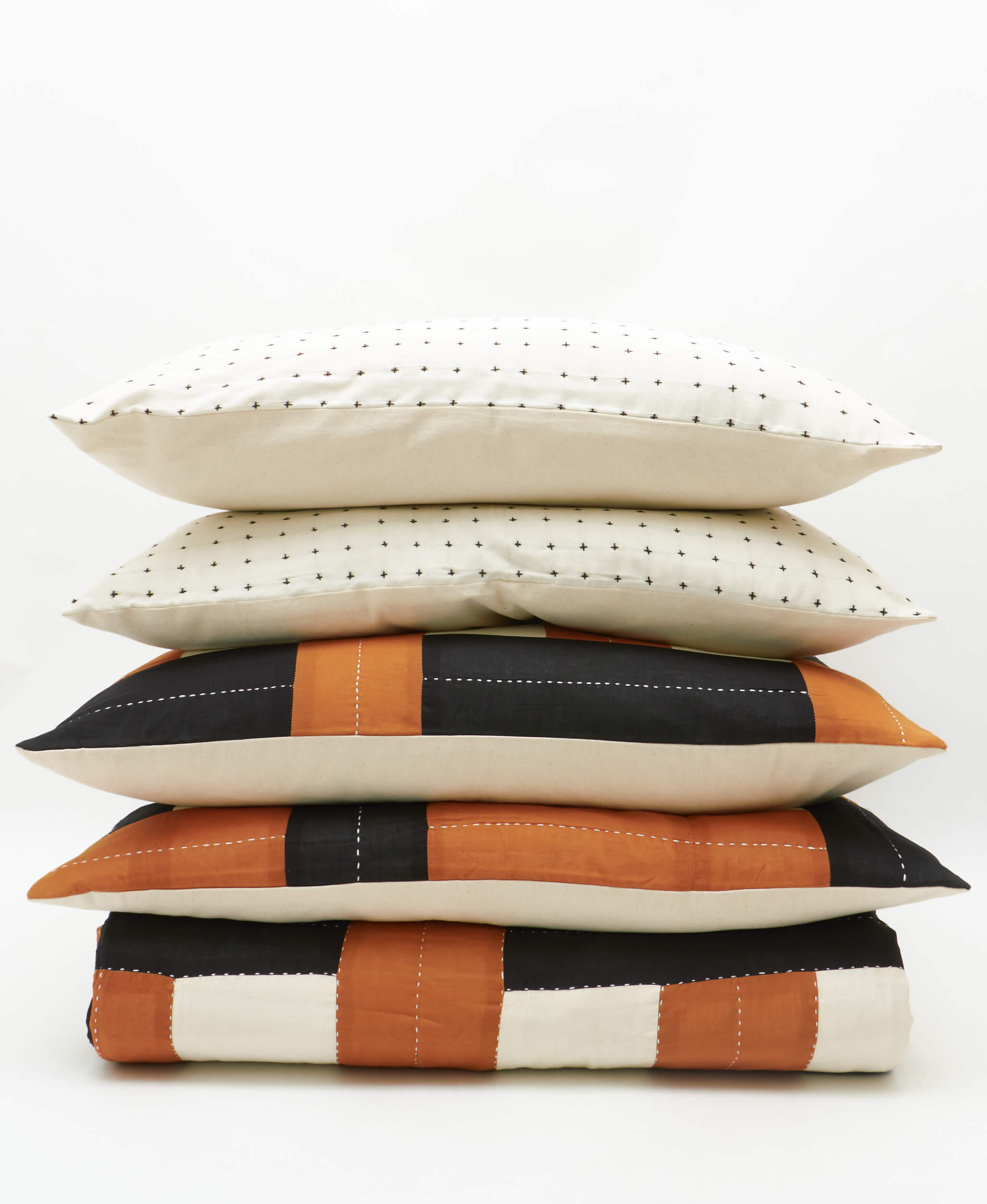 Stack of decorative pillows with different patterns on a white background