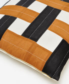 Close-up of a striped pillow with brown, black, and white colors on a light background