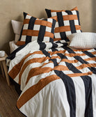 Striped plaid bedding with brown, black, and white patterns on a bed in a room