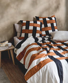 modern bed with geometric plaid bedding and checkered pillows against a beige wall