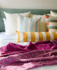 bright and colorful modern throw pillows on a bed with a green headboard