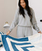 woman in gray sweatpants making children's bed with Anchal Project's fracture quilt made from GOTS certified organic cotton