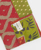 red and green Kantha quilt throw with a tag featuring the hand stitched signature of the maker