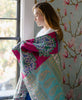 woman wrapped in a paisley kantha quilt throw looking out of a window 