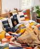 woman stretching in colorful checkered bedding and matching euro sham pillows by Anchal Project