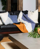 quilted throw blanket in Naari colorblock design draped on black leather sofa