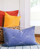 colorful organic cotton throw pillows in wicker rattan floor basket by Anchal