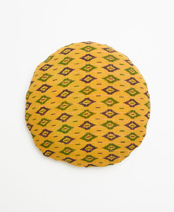 Mustard yellow round kantha throw pillow with a purple and green geometric pattern through out 