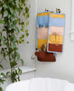 Peach, blue, yellow, and red travel organizer hanging on wall with hairbrush and makeup