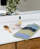 small hanging travel organizer in blues and greens on bathroom counter by Anchal Project
