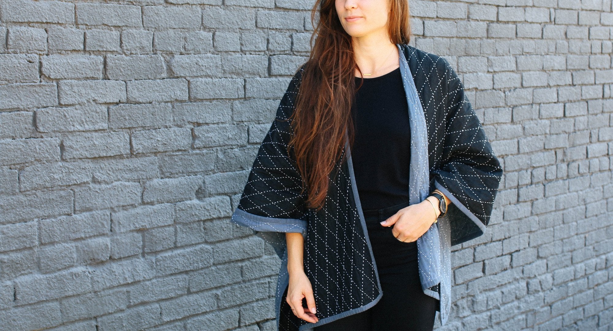 Shawl from Anchal's Narrative collection being modeled in front of a black brick wall