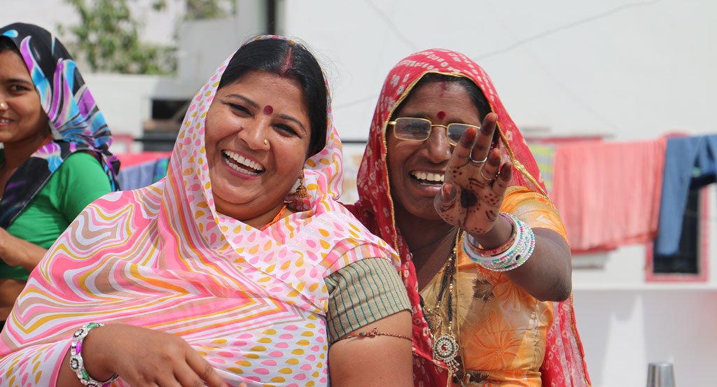 Two Indian women dressed in Sari's laughing with joyful expressions at an artisan workshop held by Anchal