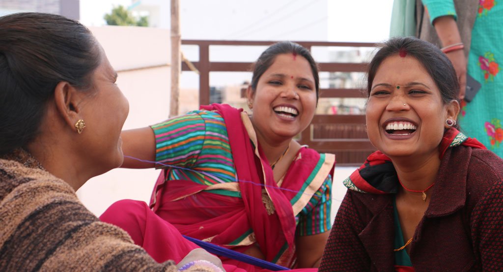 Three Anchal artisan women laughing with joyful expressions