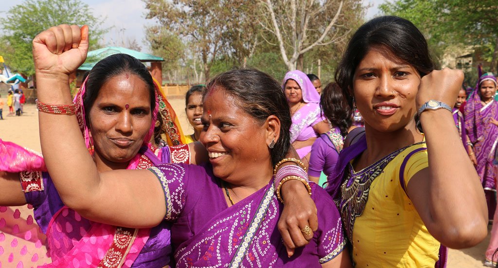 Three artisans with their arms around each other holding up fists as a sign of empowerment