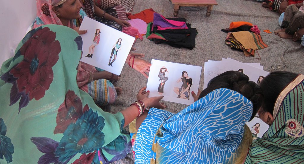  Artisans gathered at a design workshop looking at photos of the results of their work for the first time  